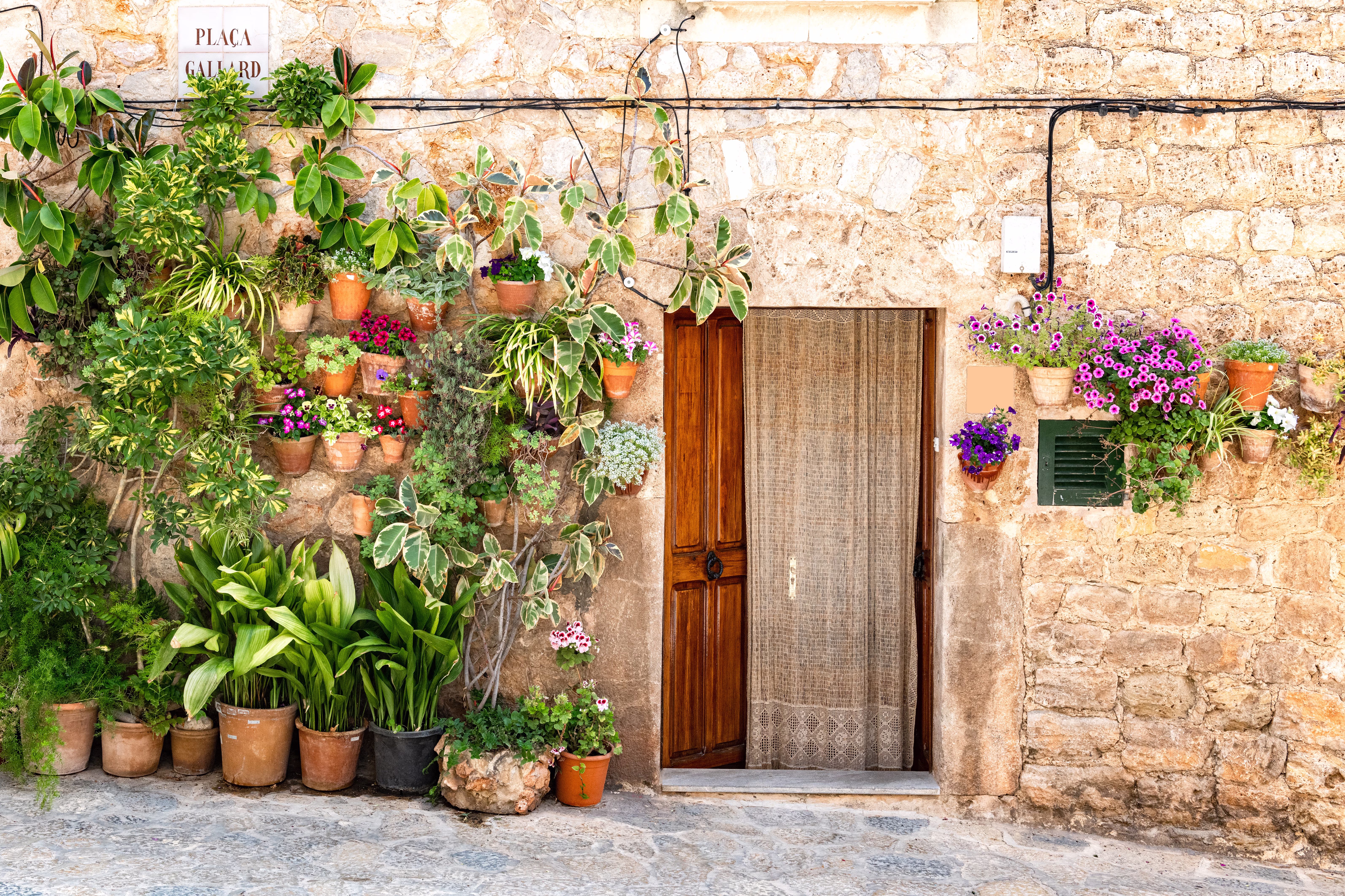 Many Mediterranean planted pots decorate the house wall Many Mediterranean planted pots decorate the house wall