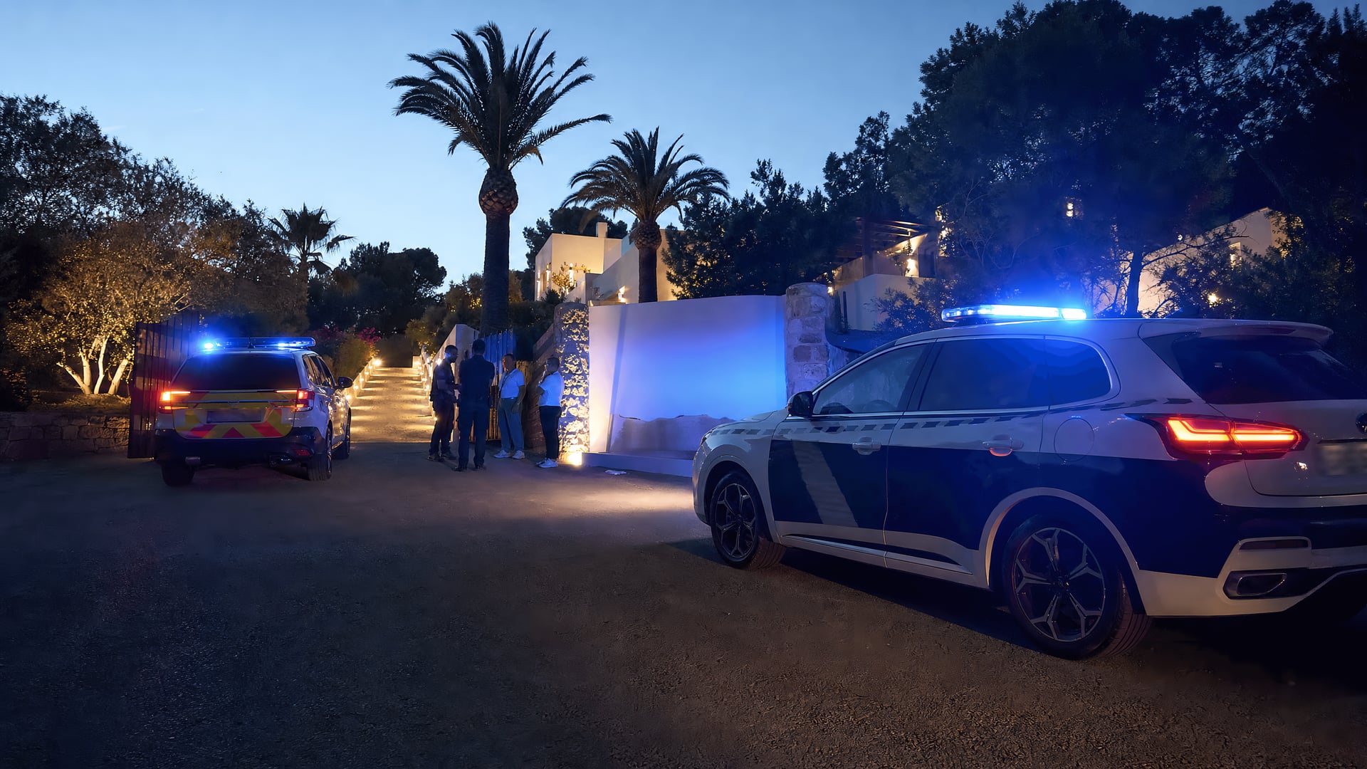 Police vehicles outside an Ibiza villa driveway after an illegal party raid.